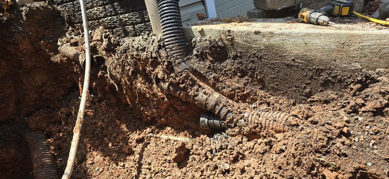 Corrugated drainfield pipe exposed during a repair in red Virginia clay